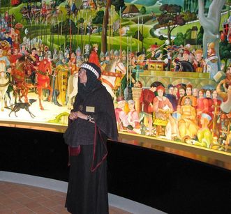 Monastery tour guide in historical clothing in front of the mural of the House of Staufen at Lorch Monastery